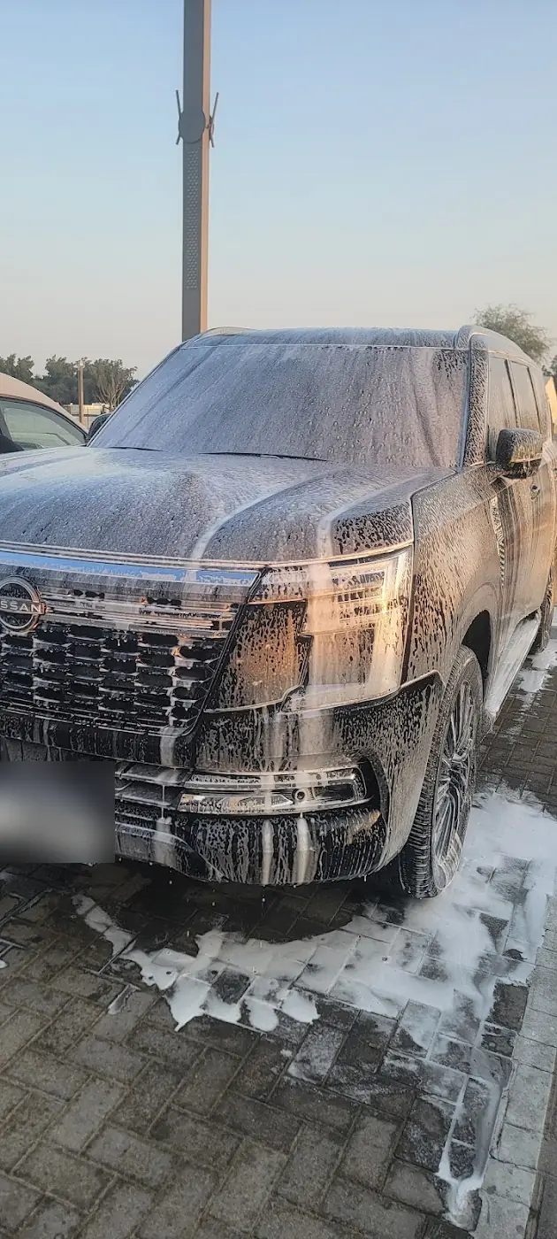 A Nissan Patrol covered in white foam under a blue sky, photo by Smart Car Cleaning