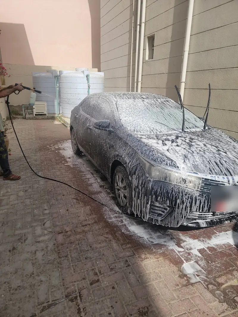 A sedan under thick white foam on a villa driveway
