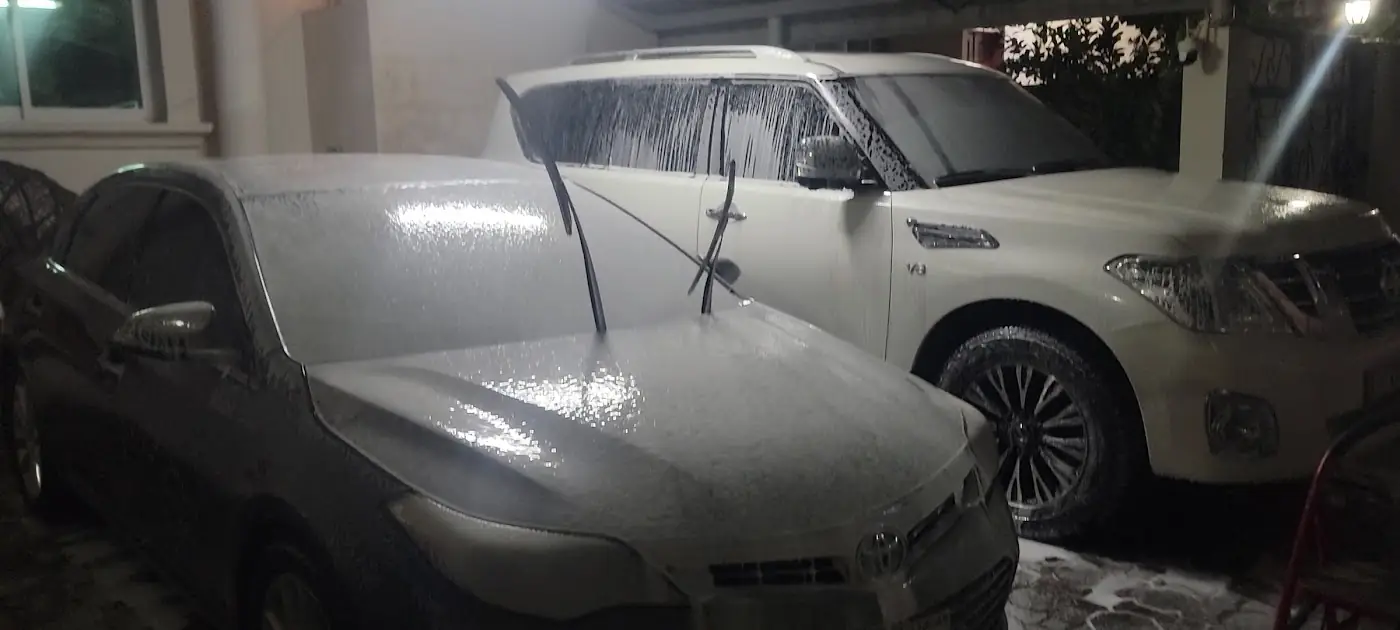 A Toyota and a Nissan Patrol both covered in foam at night