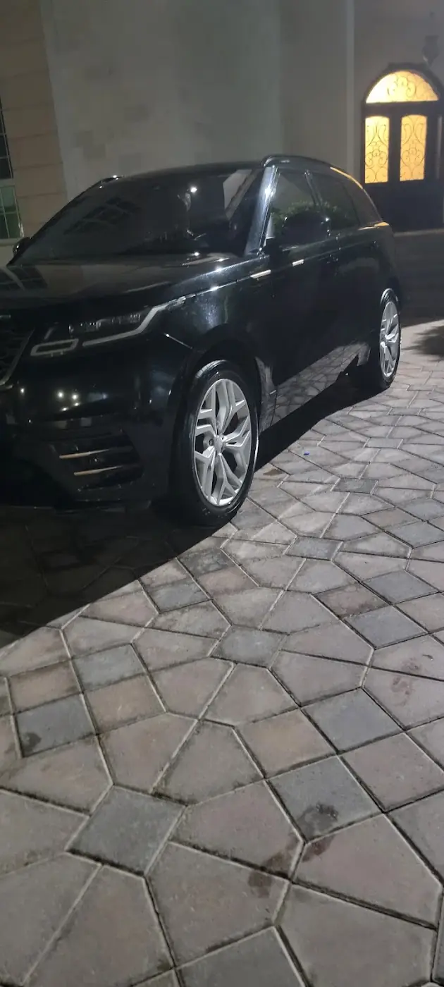 A clean black Range Rover glossy under a villa lamp